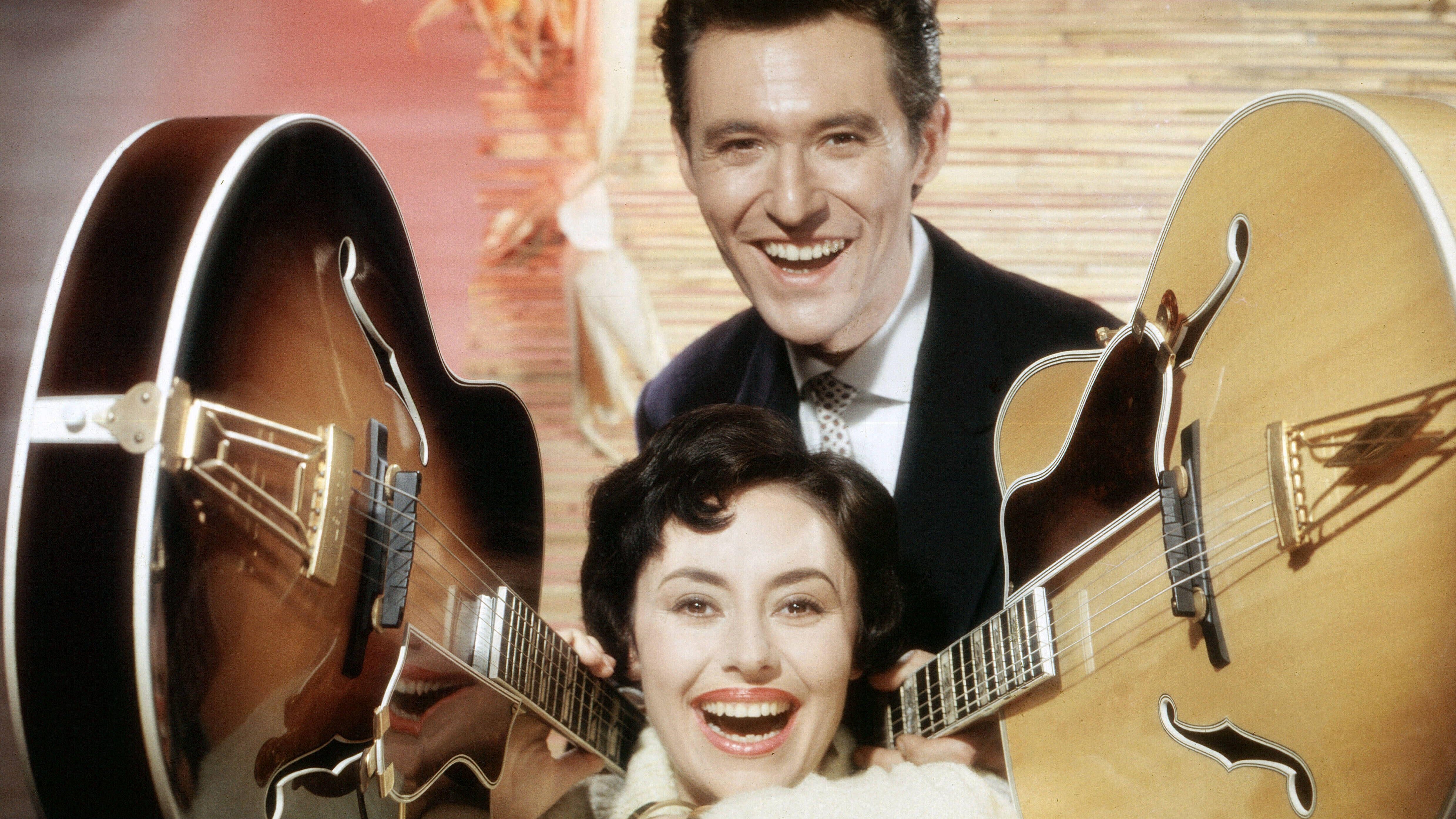 Mann und Frau die von 2 Gitarren flankiert sind