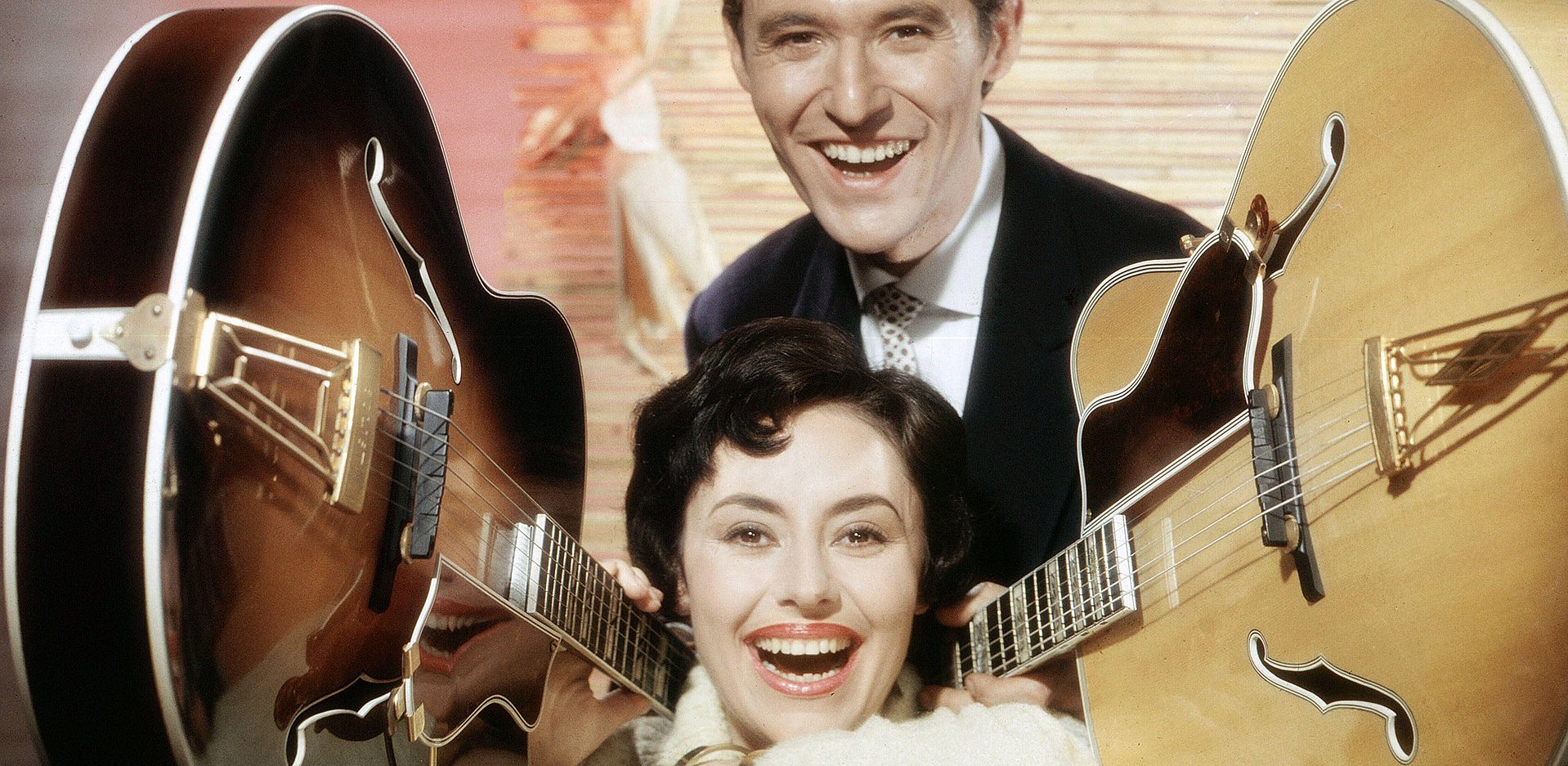 Mann und Frau die von 2 Gitarren flankiert sind